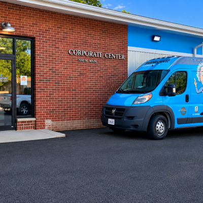 Blue Intelligent Service van parked outside a brick office building, offering plumbing and HVAC services.