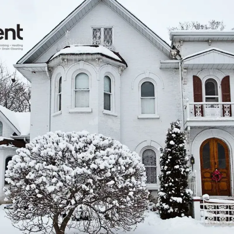 Snow-covered house with logo of Intelligent Service for plumbing and heating solutions.