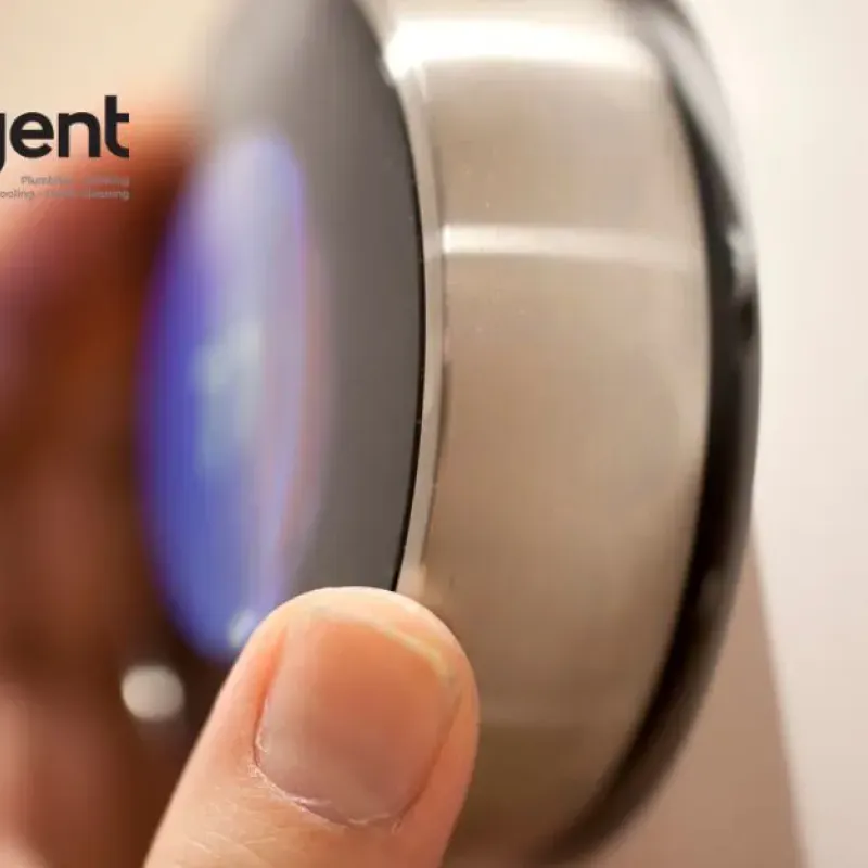 Hand adjusting a smart thermostat with Intelligent Service logo for heating and cooling solutions.