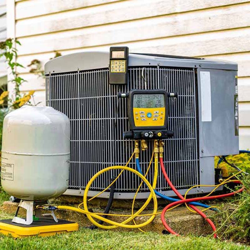 HVAC unit maintenance with gauges and tank outside a house. Heating and cooling system repair concept.