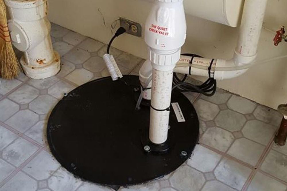 Sump pump system in basement with check valve and pipes installed on tiled floor.