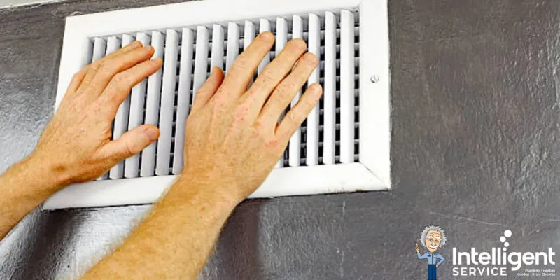 Hand adjusting water heater connections for maintenance in a tiled bathroom. Intelligent Service logo visible.