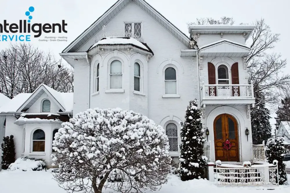 Snow-covered house with logo of Intelligent Service for plumbing and heating solutions.