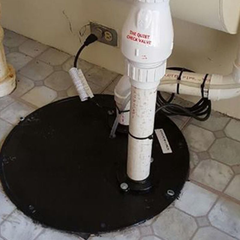 Sump pump system in basement with check valve and pipes installed on tiled floor.