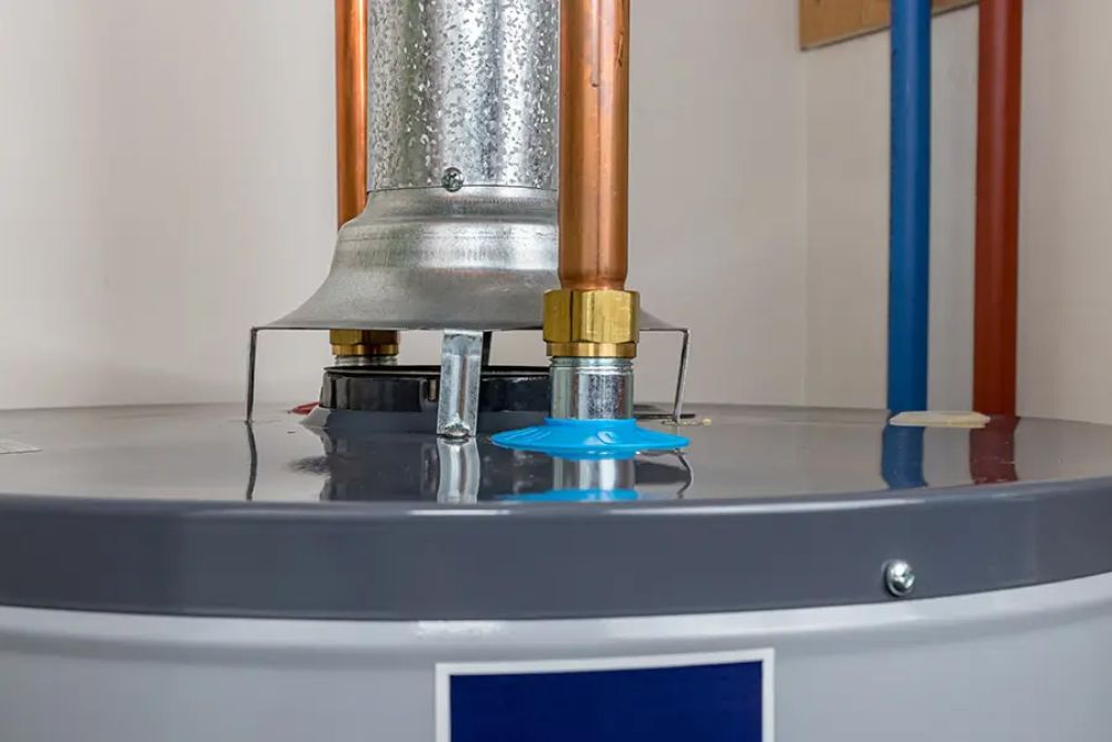 Close-up of modern water heater with copper pipes and metal vent in utility room.